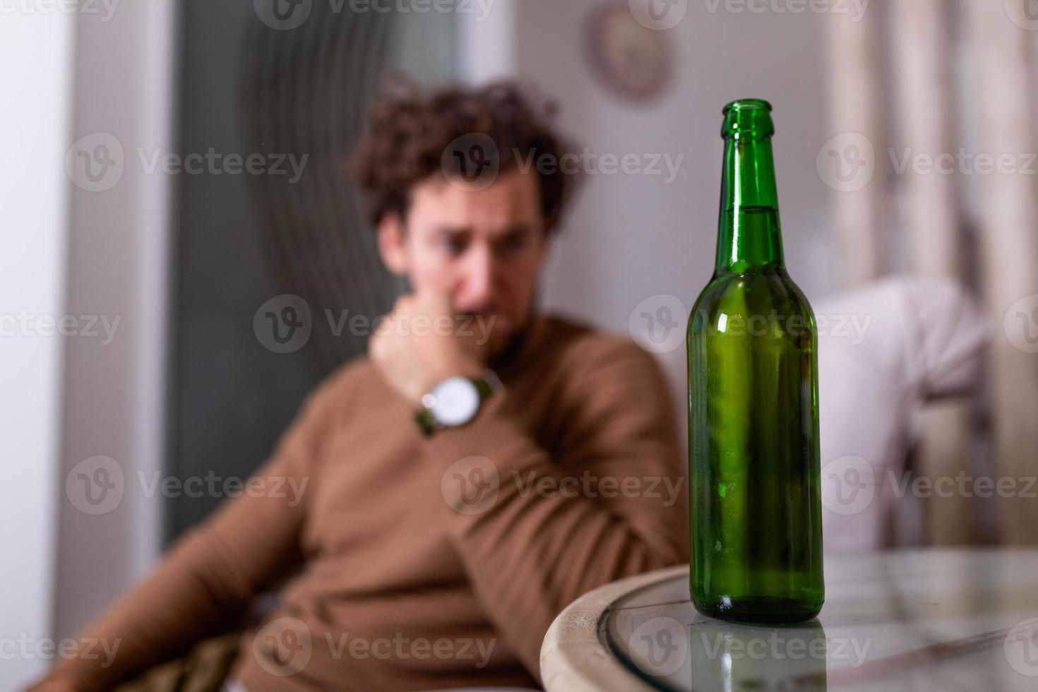 Alcoholic man reaching for bottle of beer, Man drinking home alone. alcoholism, alcohol addiction and people concept - male alcoholic with bottle of beer drinking at home alone photo