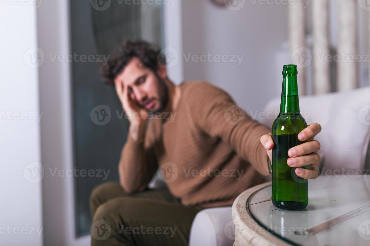 After work a depressed guy sitting on sofa, drinking a cold beer. Hand holding a glass, Man drinking home alone. alcoholism, alcohol addiction and people concept photo