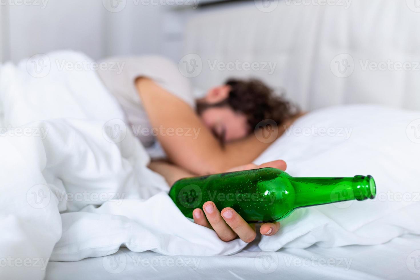 después de beber hombre adulto barbudo borracho acostado en la cama y durmiendo después de beber mucho alcohol, botella vacía en la cama, alcoholismo, adicción al alcohol y concepto de personas foto