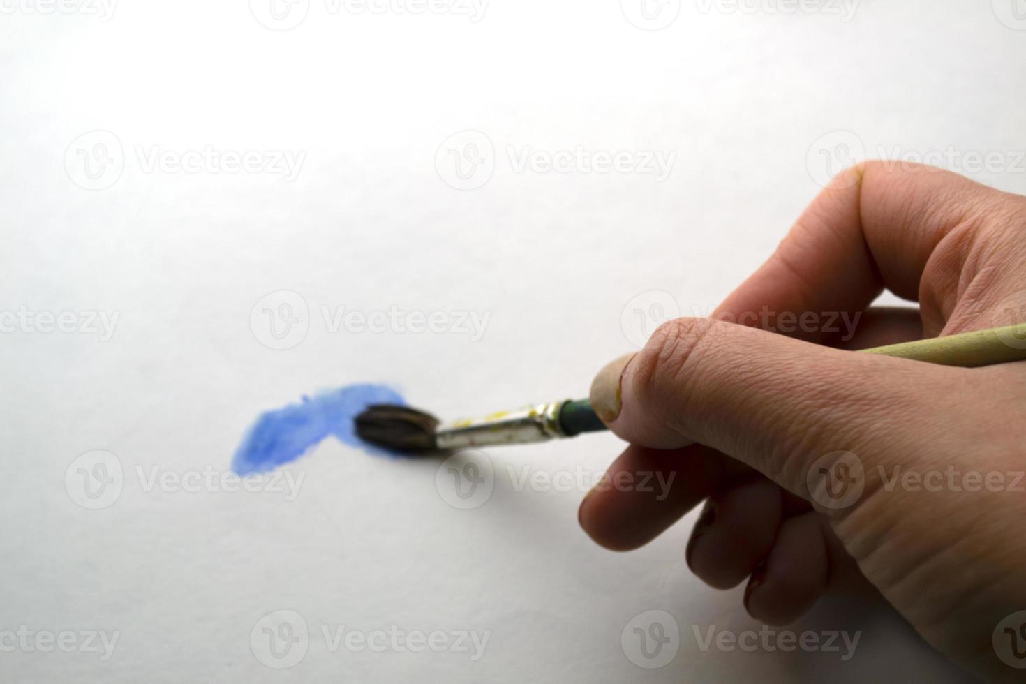 A woman's hand draws with blue paint. photo