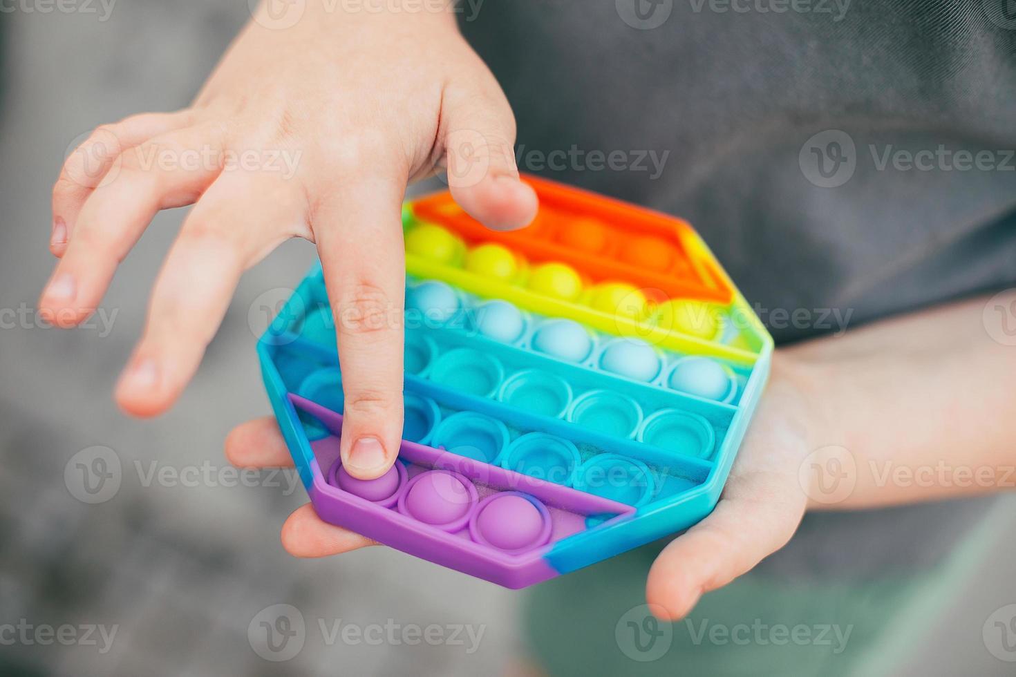 Pop it fidget toy in girl hand's. Colorful antistress kid's toy fidget photo