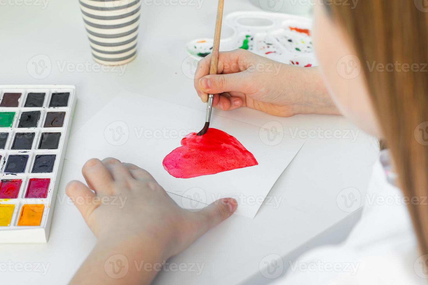 Valentine's day card made by a child. Girl drawing card for the holiday with watercolors photo