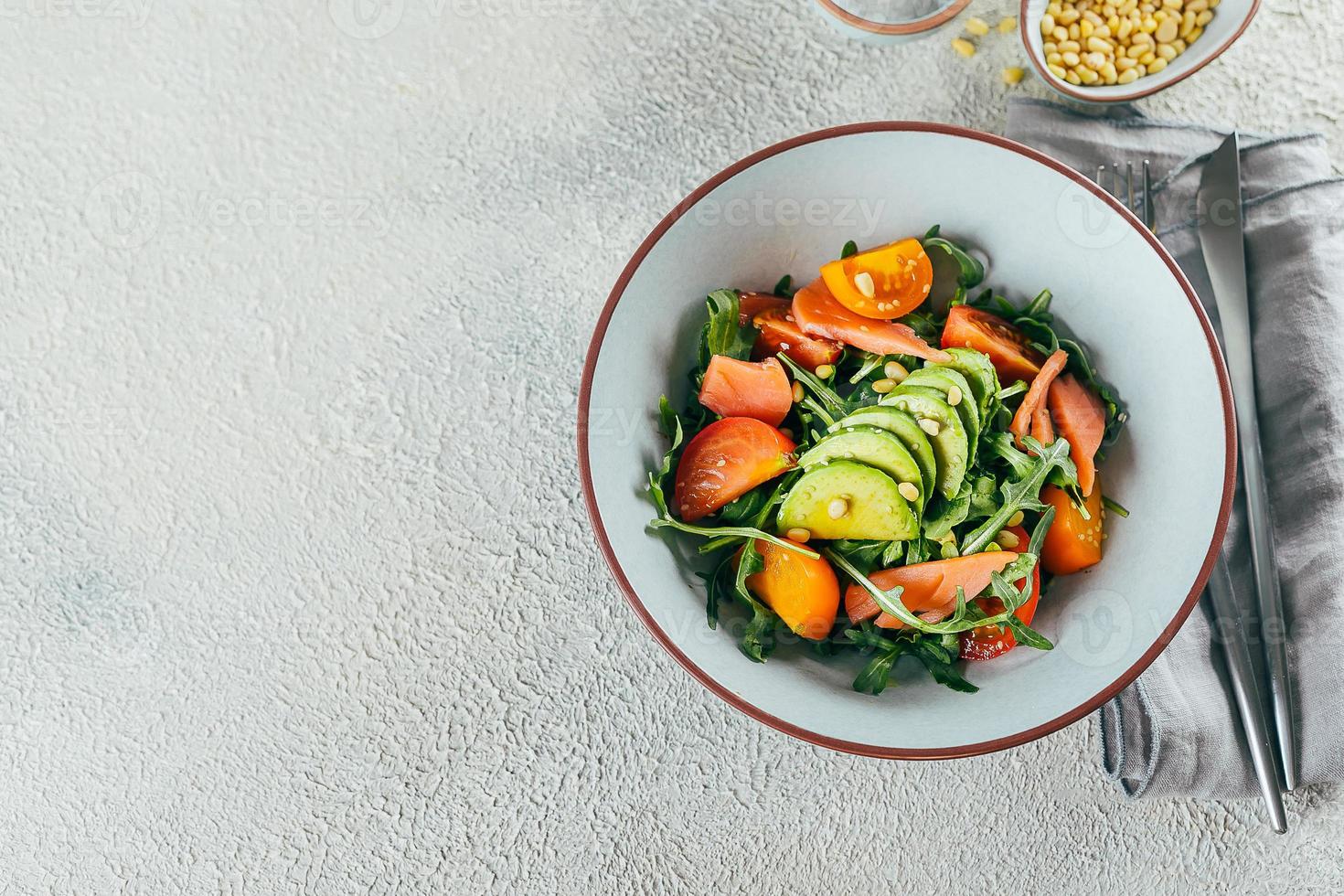 Healthy vegan salad bowl with salmon, tomato, avocado, arugula. Delicious balanced food concept. photo