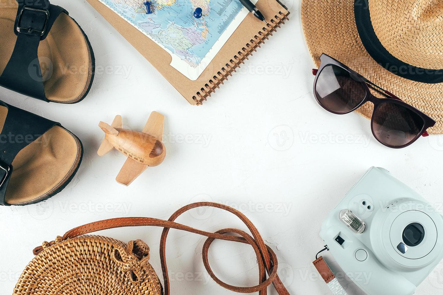 Travel flat lay. Handbag, straw hat, sunglasses, sandals, camera, notebook, map, airplane. Top view photo