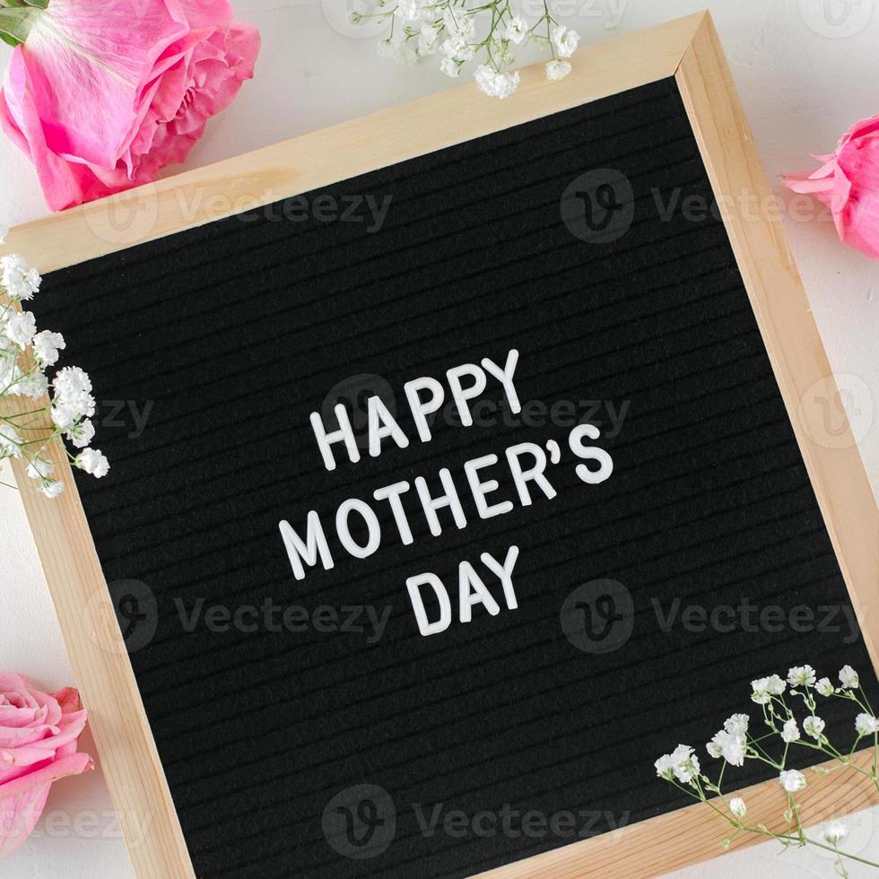 Happy mother's day text on black letters board, pink roses, gypsophila. Greeting card concept photo