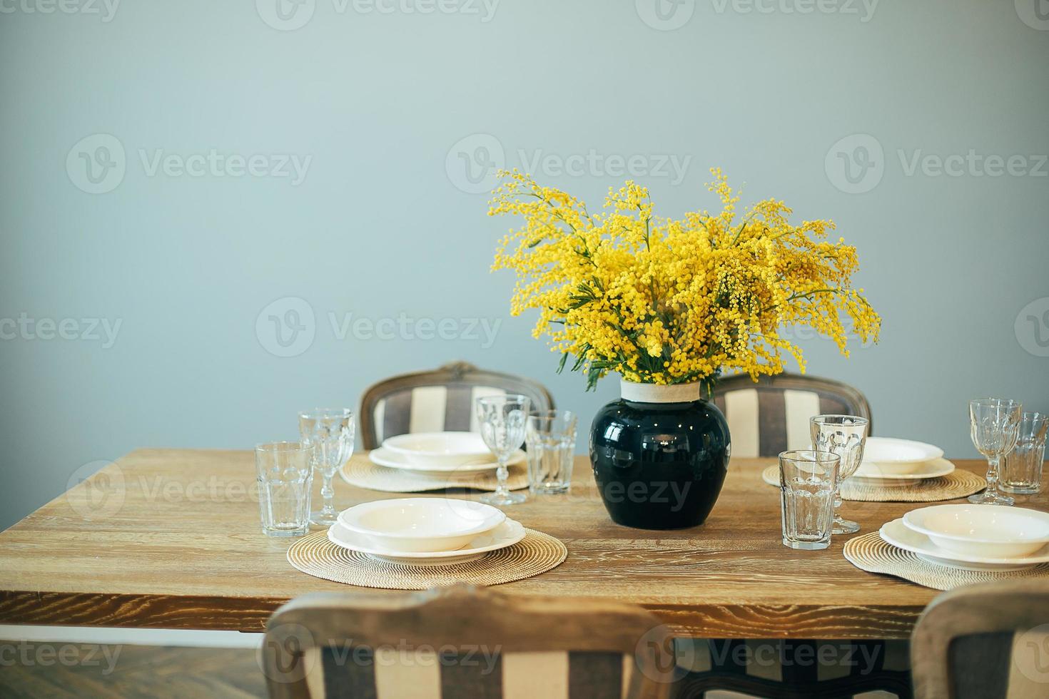 Festive Easter table setting. Branches of mimosa in vase. Home interior photo