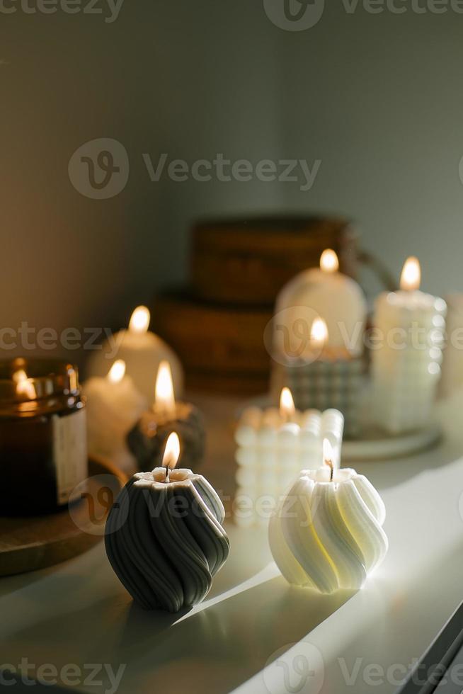 Cozy burning candles on white shelf. Concept of winter or autumn home interior decor photo