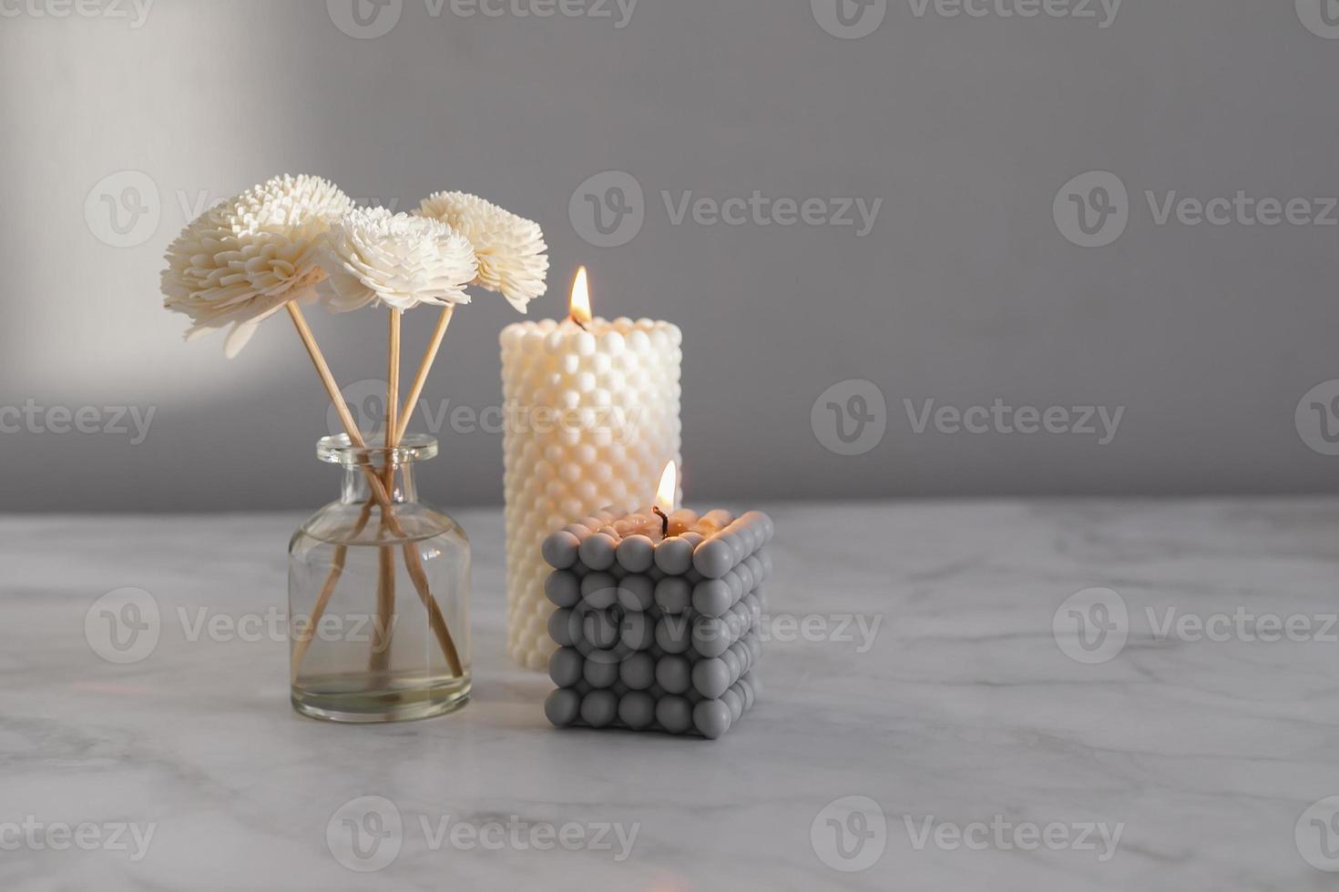 Home aroma fragrance diffuser and burning candles on marble background. Interior elements. photo
