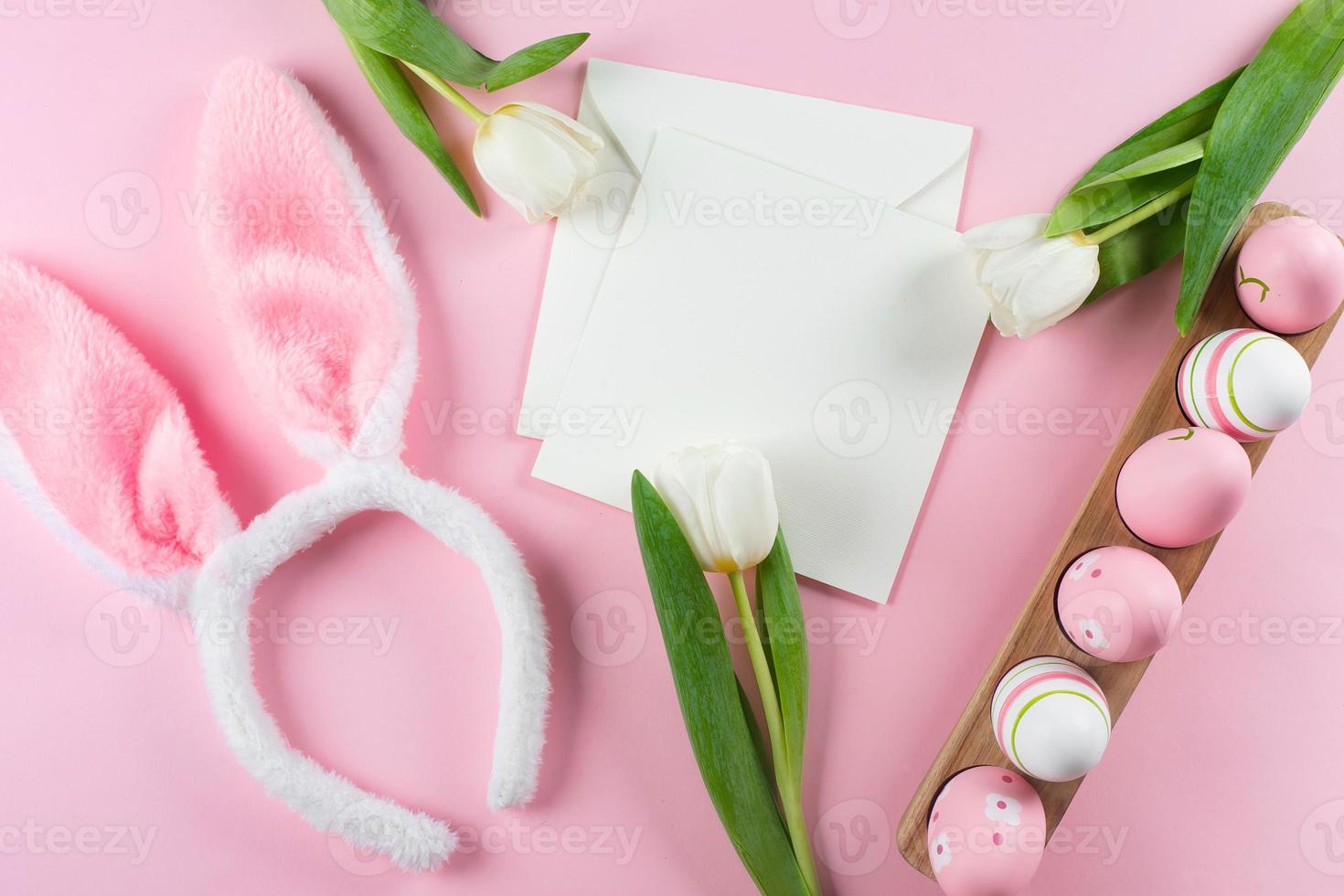 Easter background with easter eggs, fluffy bunny ears, white tulips and empty card for text. Mockup photo