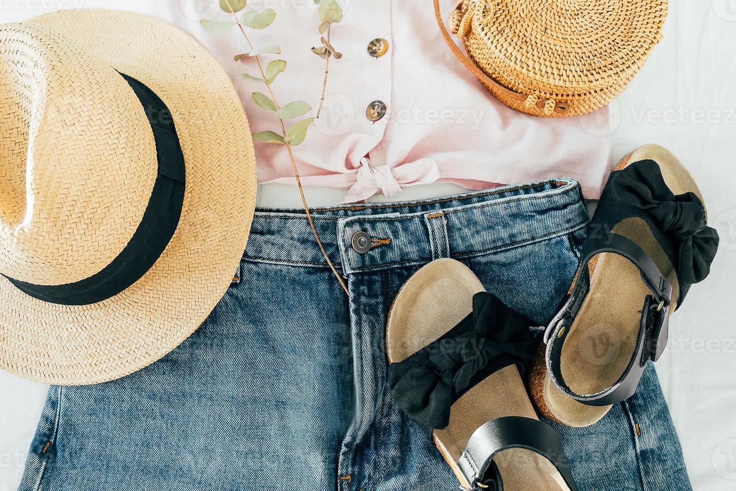 concepto de blog de belleza. ropa femenina de verano, accesorios. sandalias, camisa de mezclilla, top, sombrero, bolso de mimbre foto