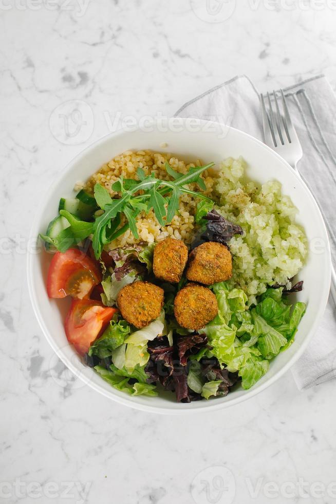 Falafel and fresh vegetables mixed salad on white marble table background, top view. Vegetarian, diet food concept photo