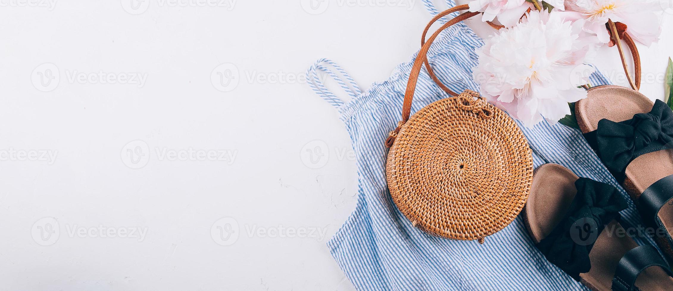 Women's fashion summer clothes. Stylish female straw hat, blue dress, rattan bag, peony. Banner photo