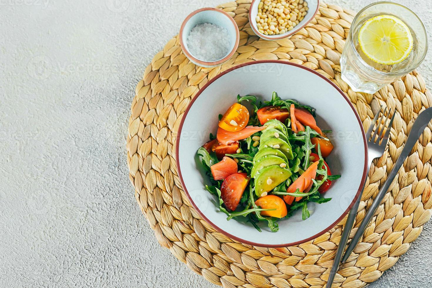 Healthy vegan salad bowl with salmon, tomato, avocado, arugula. Delicious balanced food concept. photo
