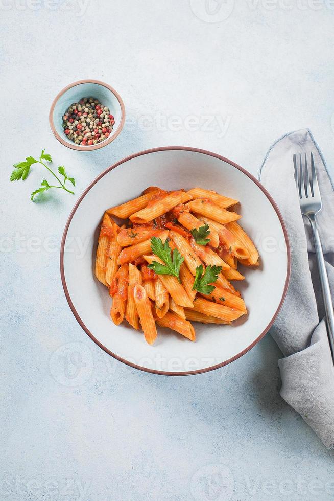 pasta penne con salsa de tomate en plato sobre mesa de fondo de piedra. vista superior. comida italiana foto
