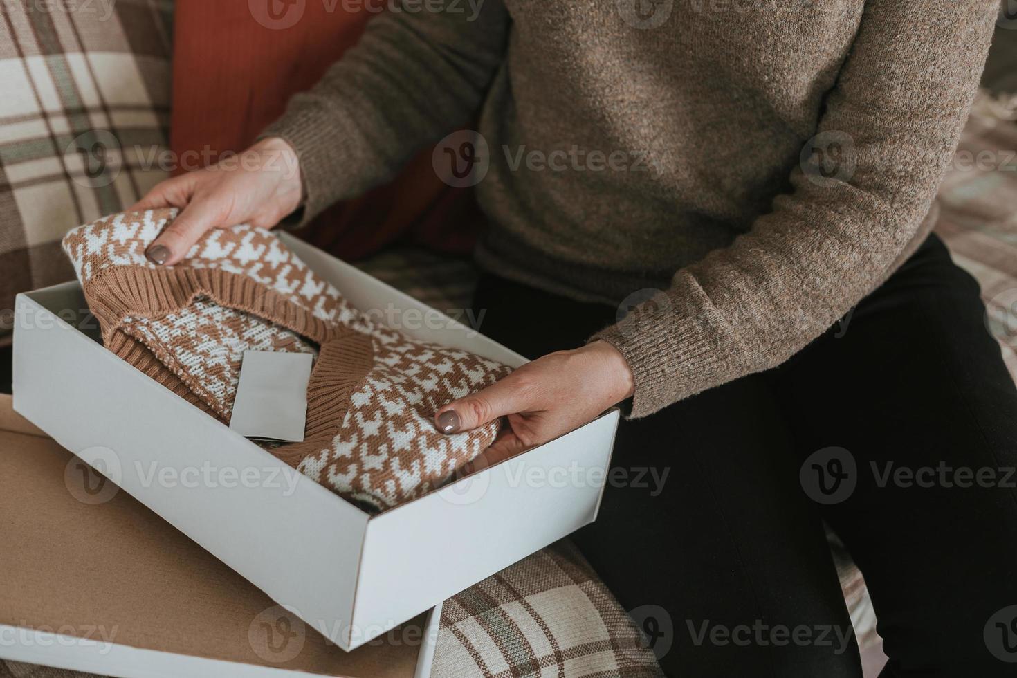 Female hands holding knitted vest or sweater. Concept of online shopping, unpacking gift photo