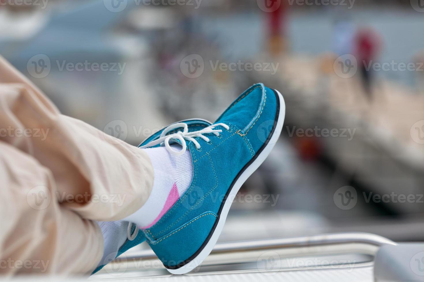 A pair of human legs in pants and bright blue topsiders photo