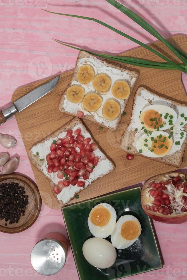 Bread has cream cheese and pomegranate boiled egg banana on pink background. photo