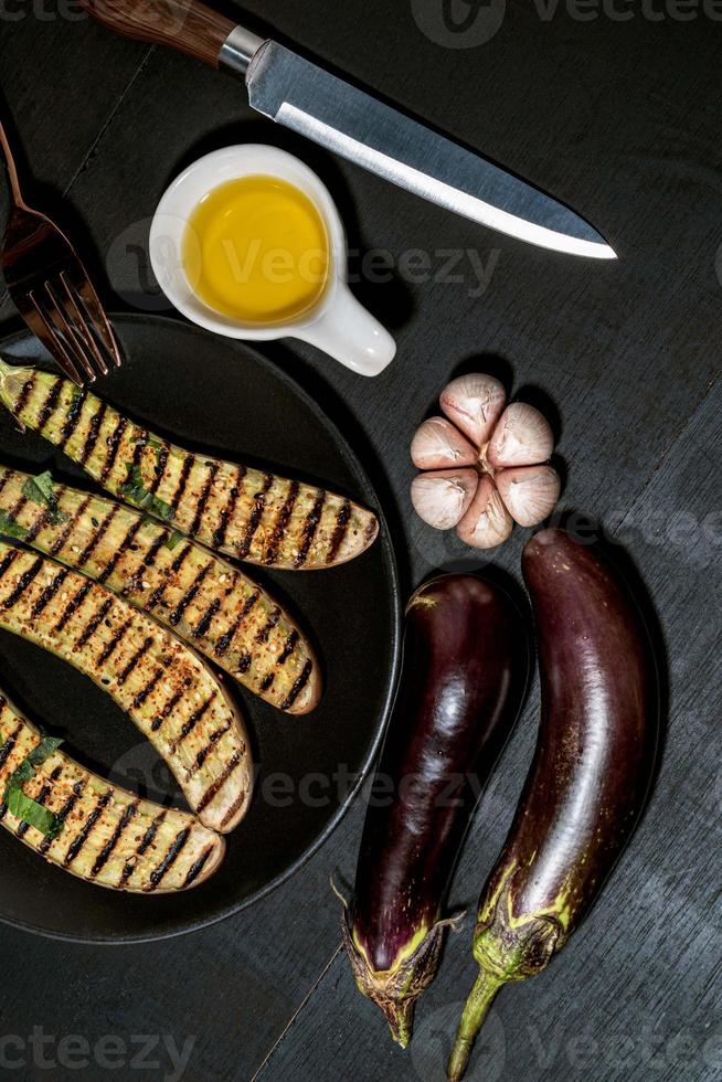 Grilled eggplants in black plate on wood background. photo