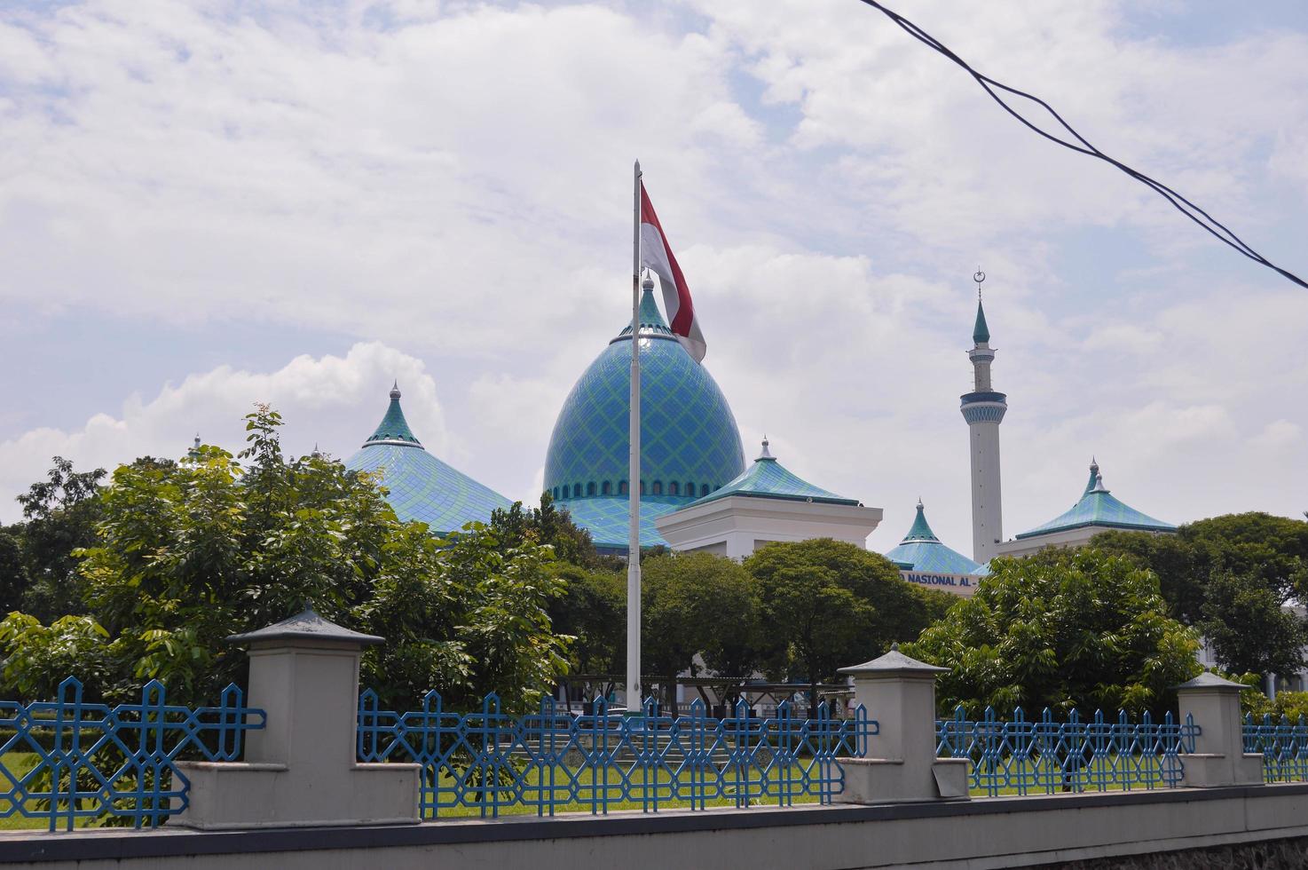 view of the grand mosque with the dome and the Indonesian flag in front of it. photo