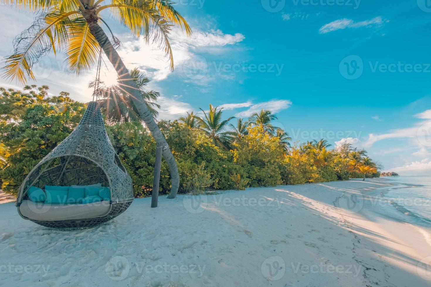 hermosa playa tropical de maldivas bajo un cielo nublado con columpios o hamacas en cocoteros. concepto de vacaciones de lujo. paisaje de viaje, costa natural. playa tranquila, vista soleada de la isla paradisíaca foto