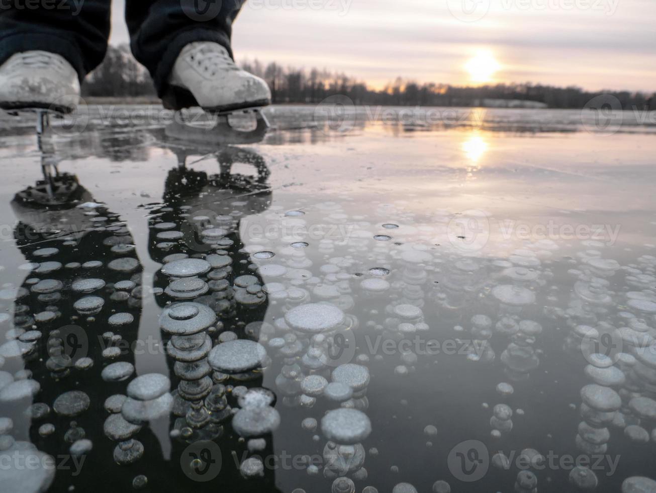 Air bubbles frozen in ice, ice skating in the evening at sunset, selected sharpness, narrow depth of field photo