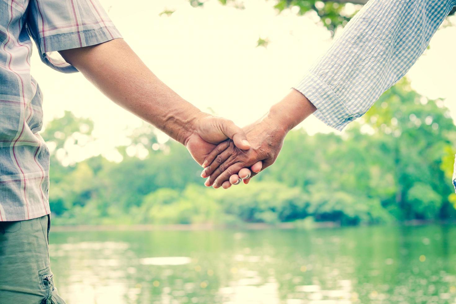 pareja asiática de ancianos tomándose de la mano, amándose y cuidándose para siempre. el telón de fondo es un hermoso río natural. foto