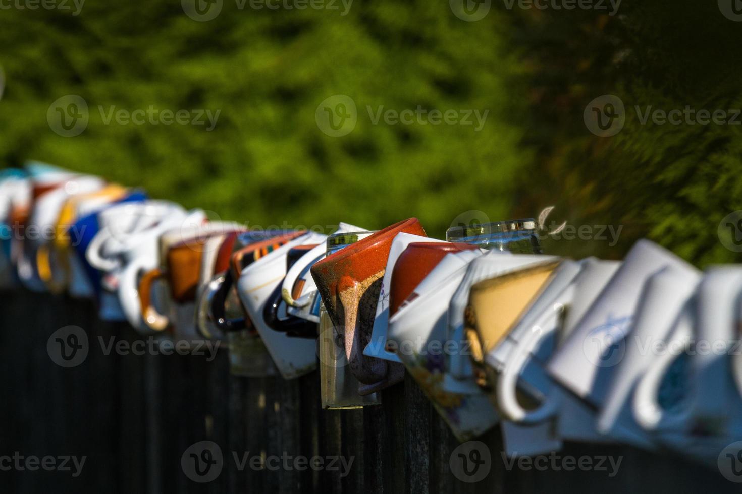 a row of coffee mugs stacked on the fence photo