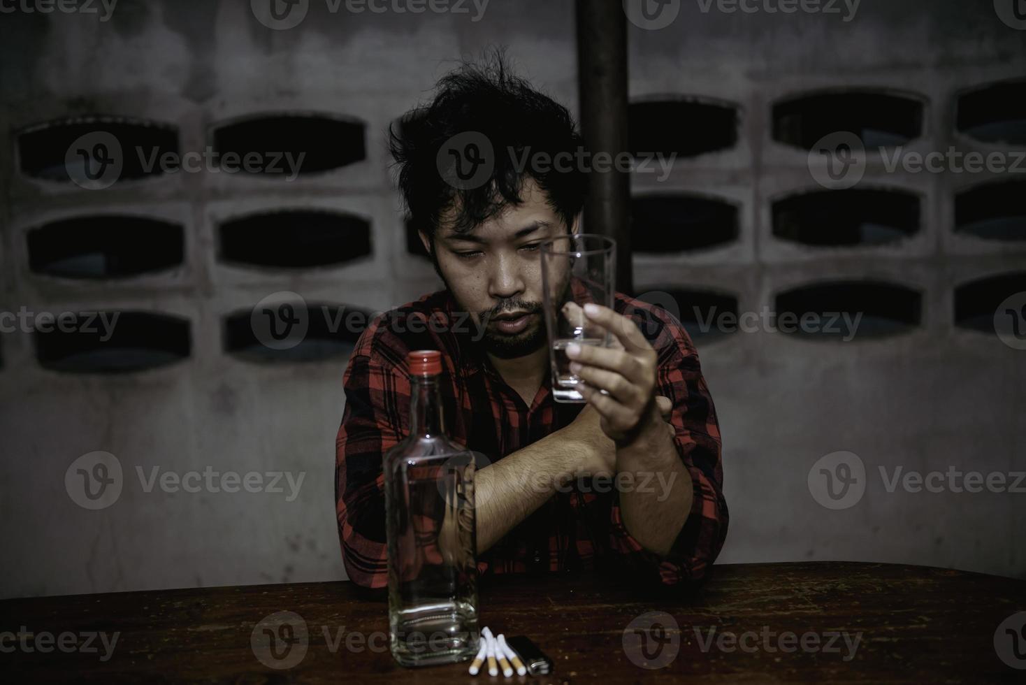 hombre asiático bebe vodka solo en casa por la noche, gente de tailandia, concepto de borracho de hombre estresado foto