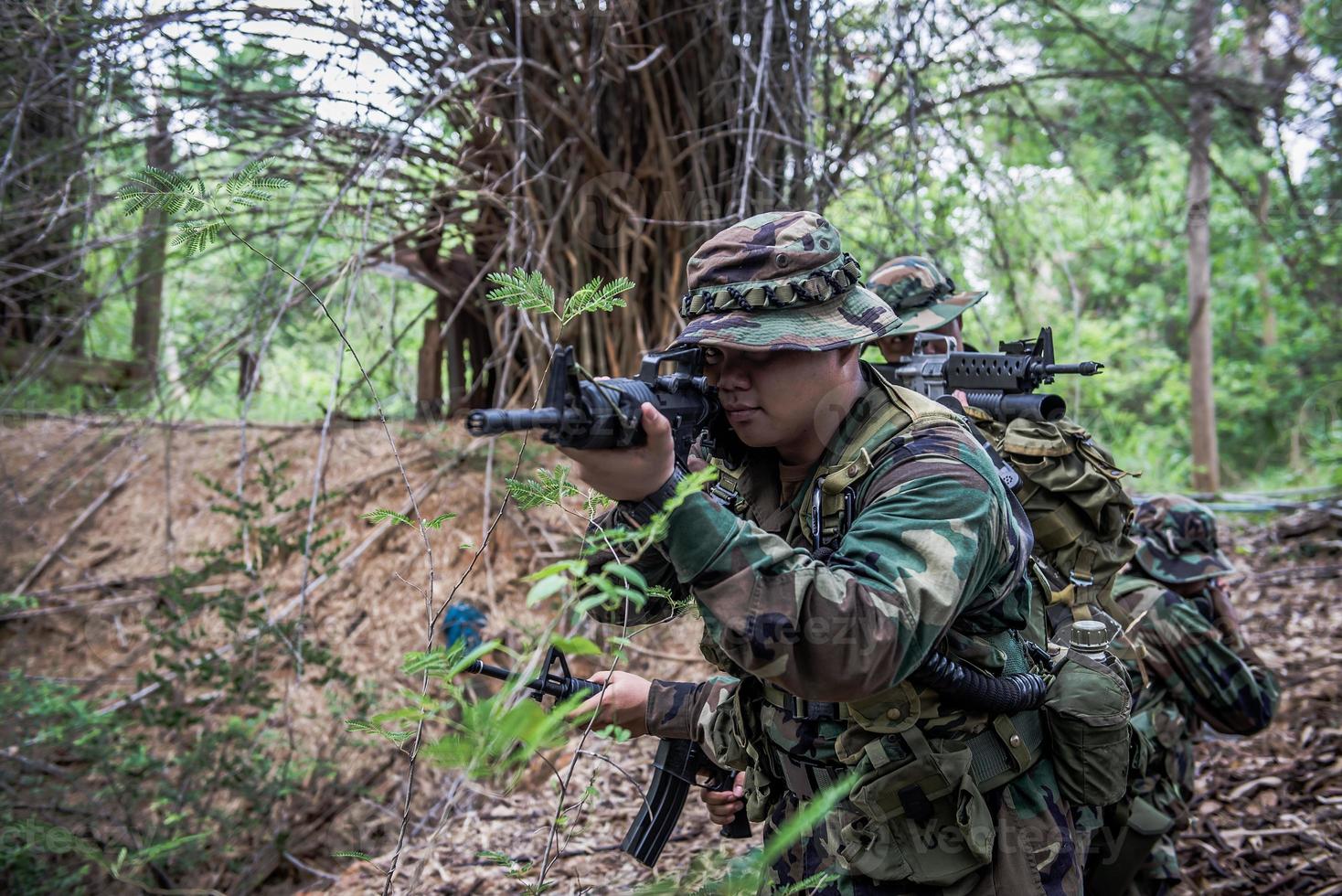 equipo de soldado del ejército con ametralladora moviéndose en el bosque, soldado de la milicia tailandesa con uniformes de combate en el bosque, pasea por la patrulla en la selva tropical. foto