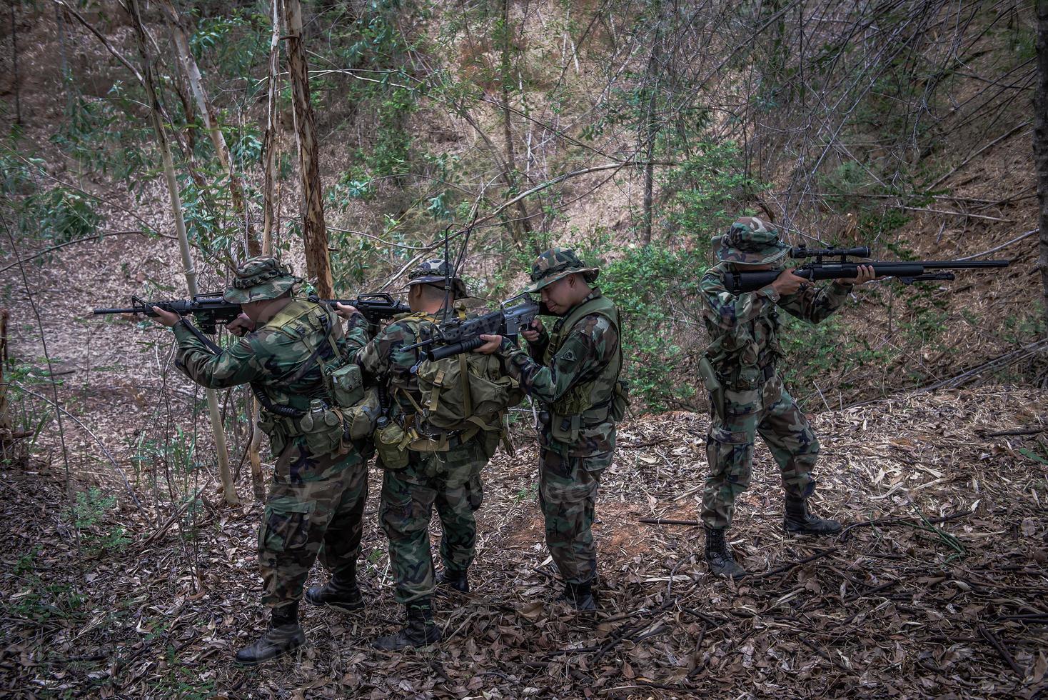 Team of army soldier with machine gun moving in the forest,Thai militia soldier in combat uniforms in the wood,Wander the patrol sloping in the rainforest. photo