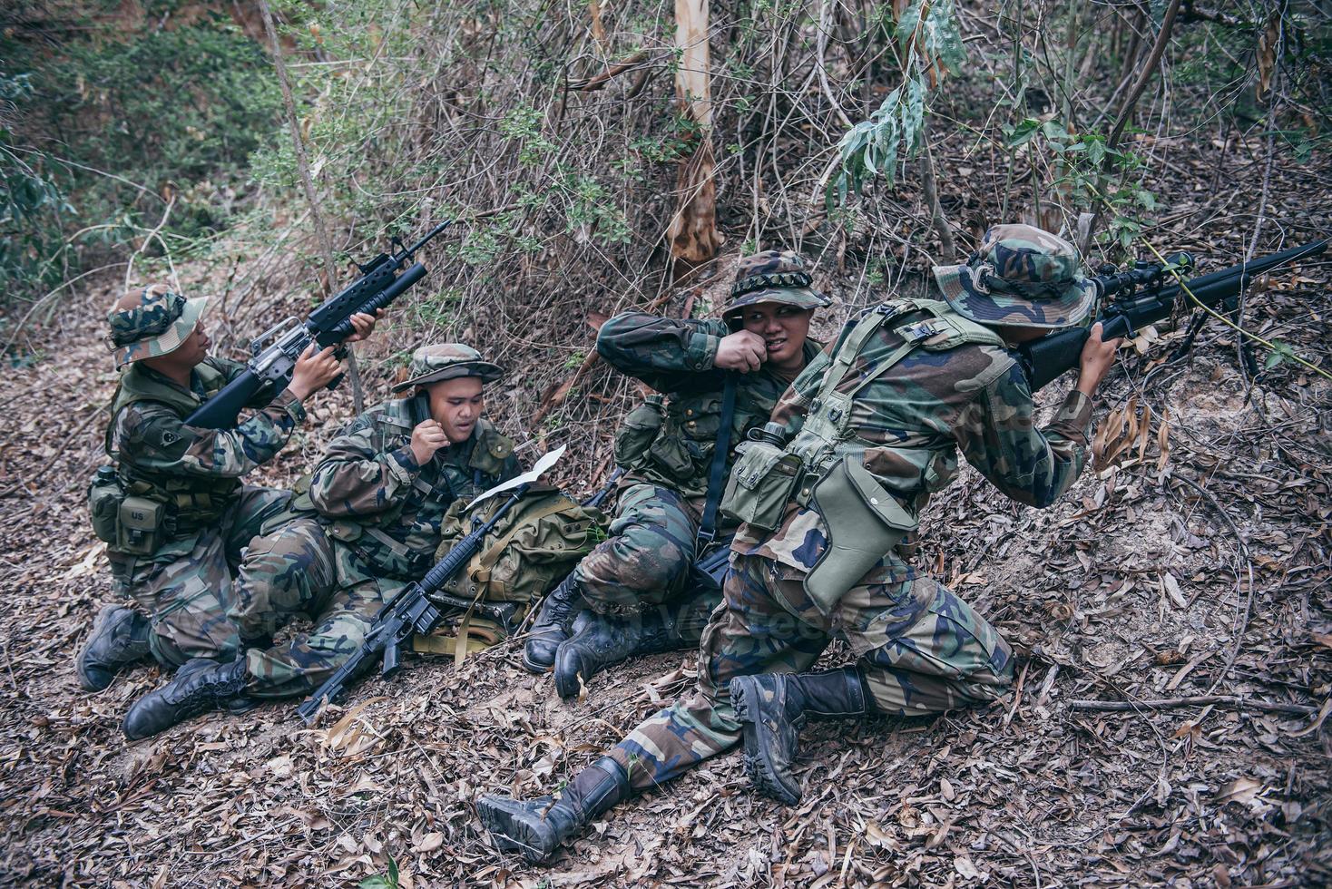 Team of army soldier with machine gun moving in the forest,Thai militia soldier in combat uniforms in the wood,Wander the patrol sloping in the rainforest. photo