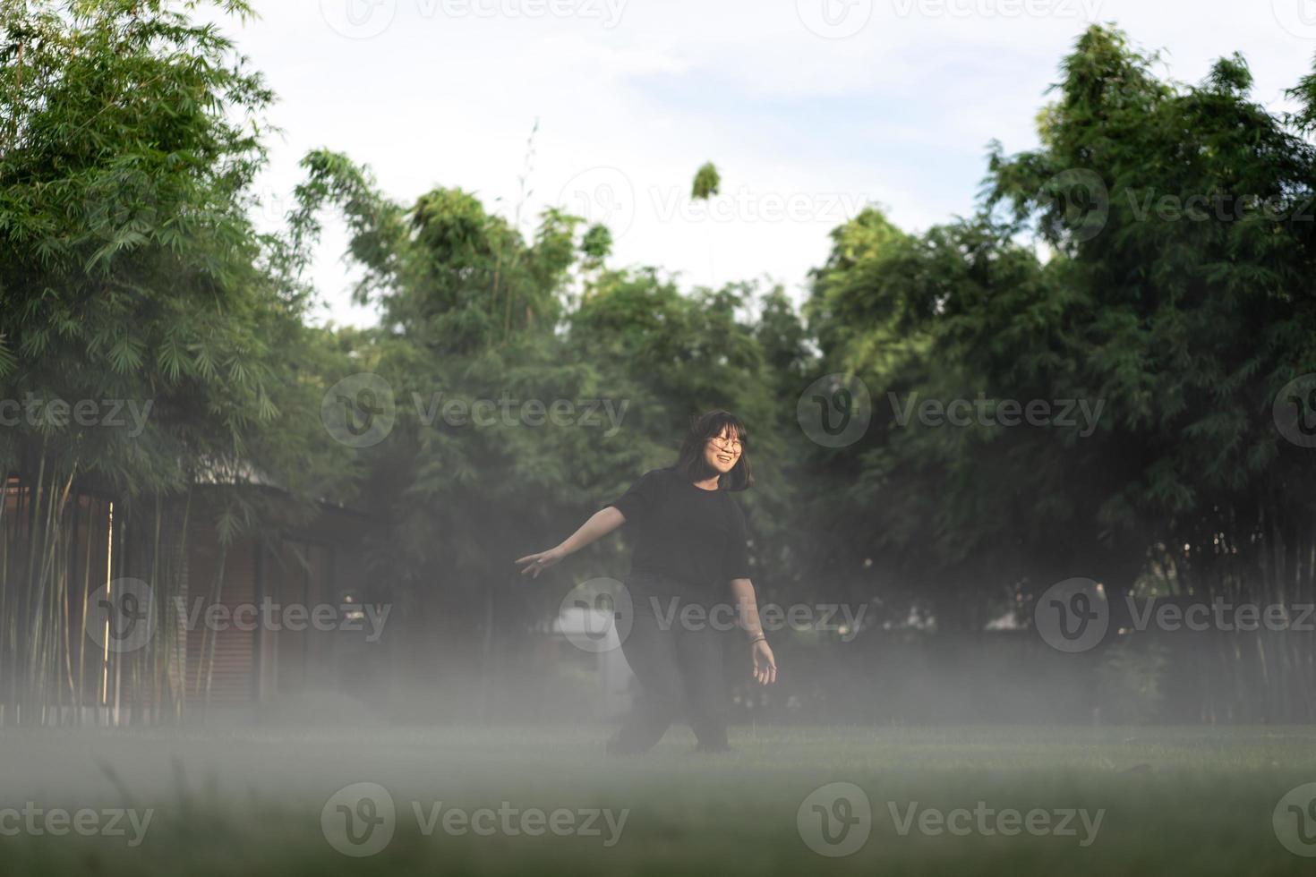 Asian short hair Woman is Joyful Jumping in the fog environment on grass field garden. photo