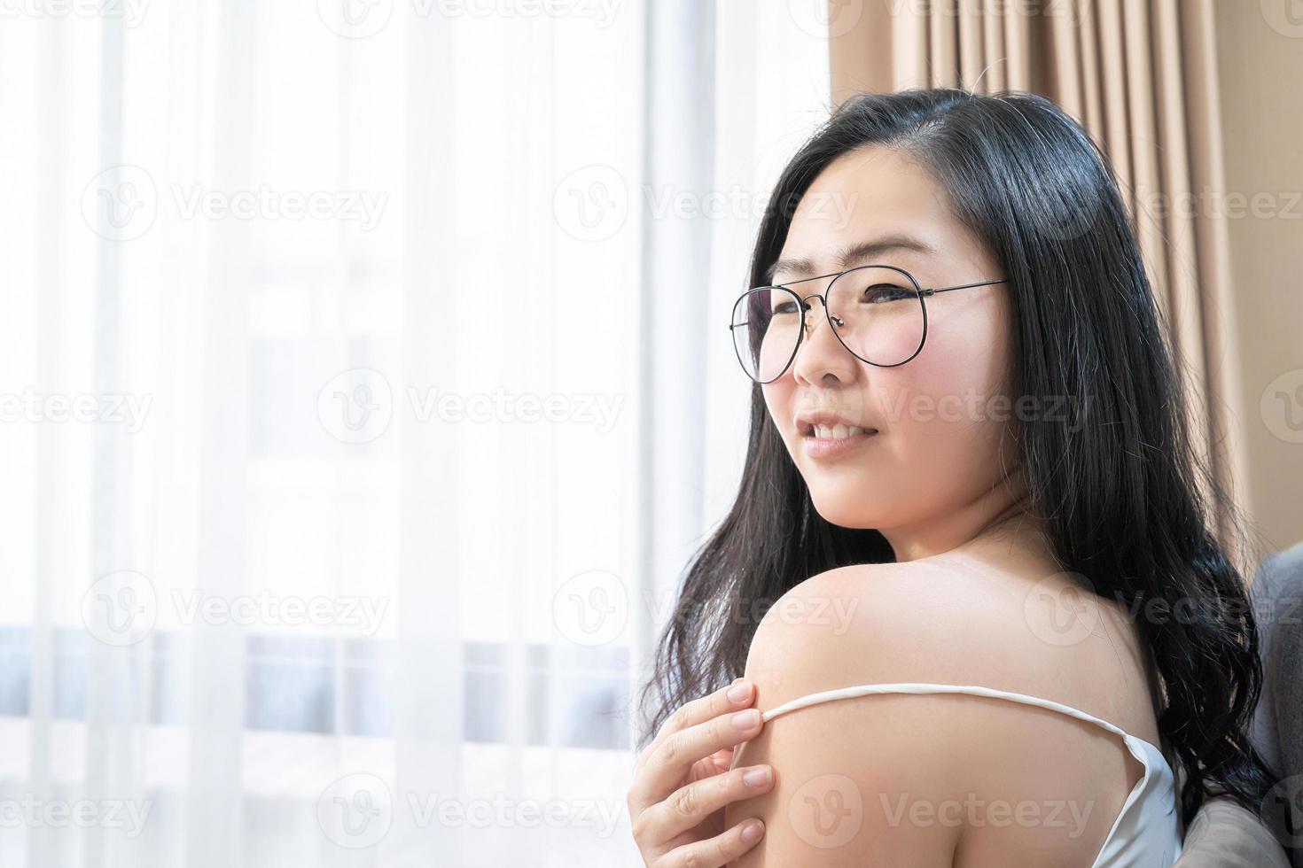 Asian Woman is posing with her sexy shoulder on her bed in the bedroom. photo