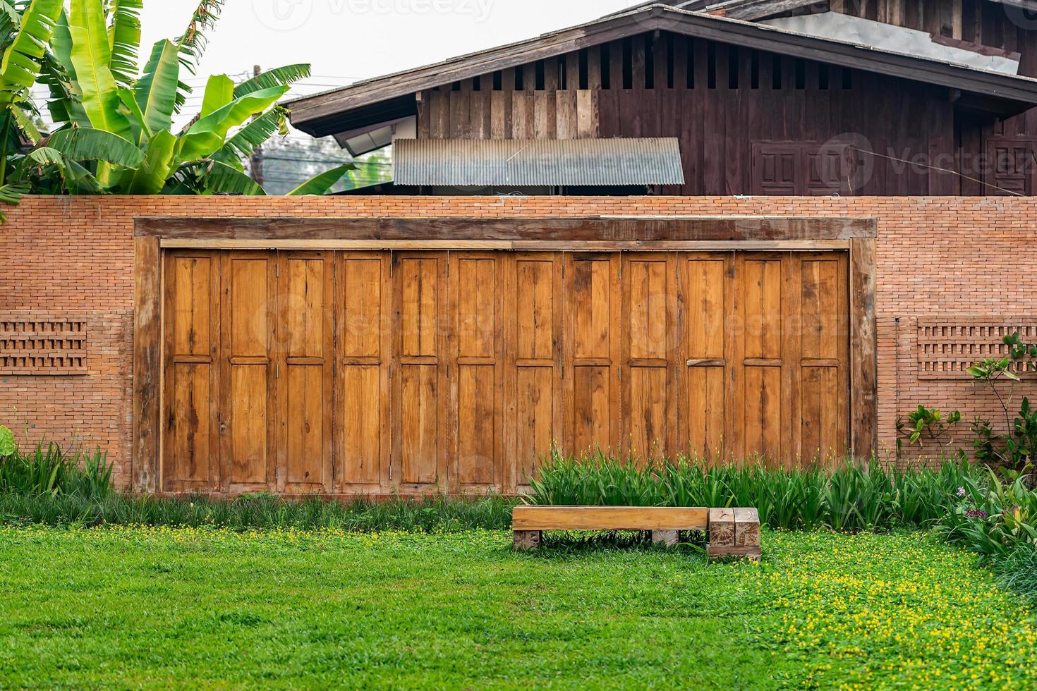 The brick wall, fence barrier is designed with a hole on top of wall in Asian style with garden grass field in the foreground photo