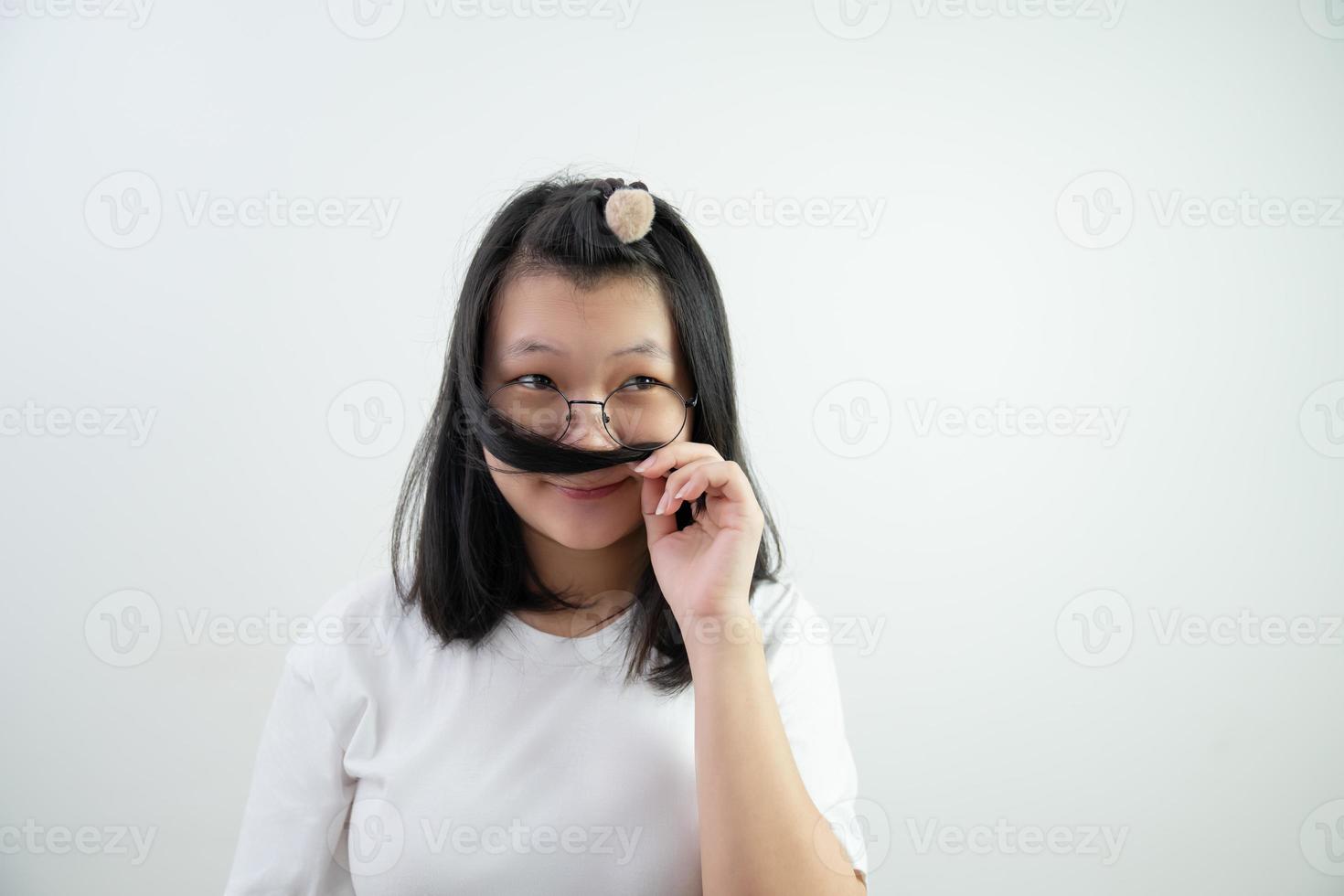 gafas asiáticas mujer joven está pensando en algo y oliendo su cabello sobre fondo blanco. foto