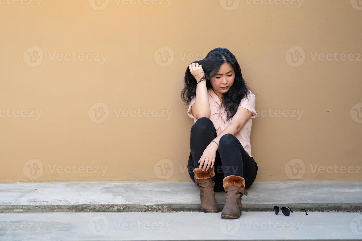 Asian woman is sitting alone on the rooftop of building with tried and disappointed mood and tone in that day. photo