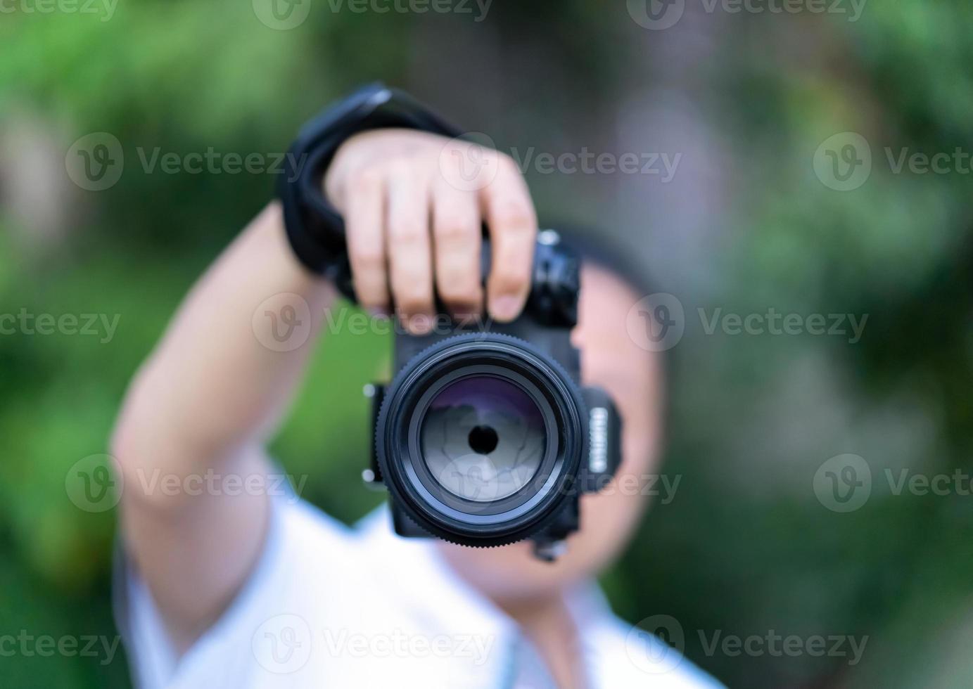 el hombre asiático sostiene la cámara de formato medio en la mano y se enfoca para disparar frente a él. foto