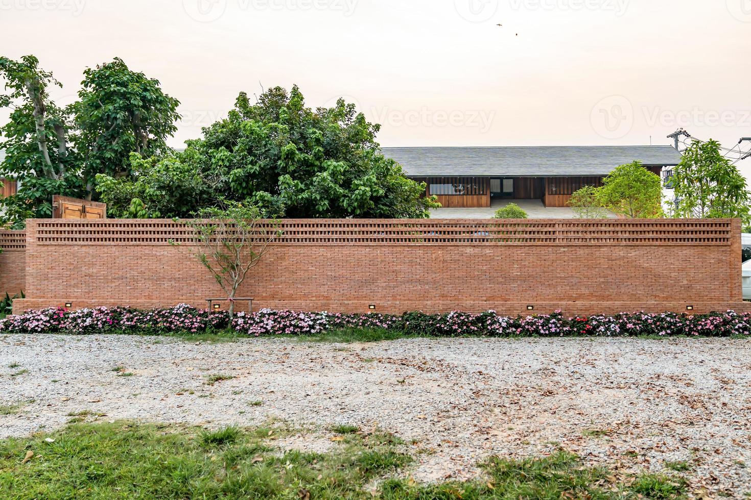 Large long brick house fence with Modern - Vintage wood building behind. photo