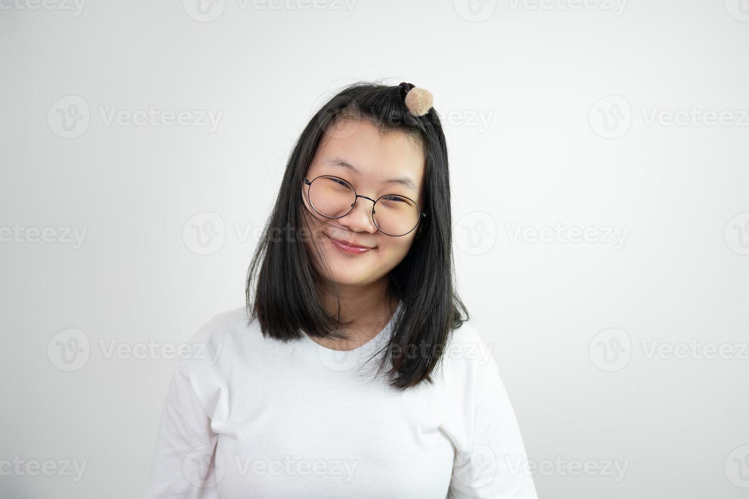 Asian Glassese Woman is looking and smiling to camera and standing on white background in studio light. photo