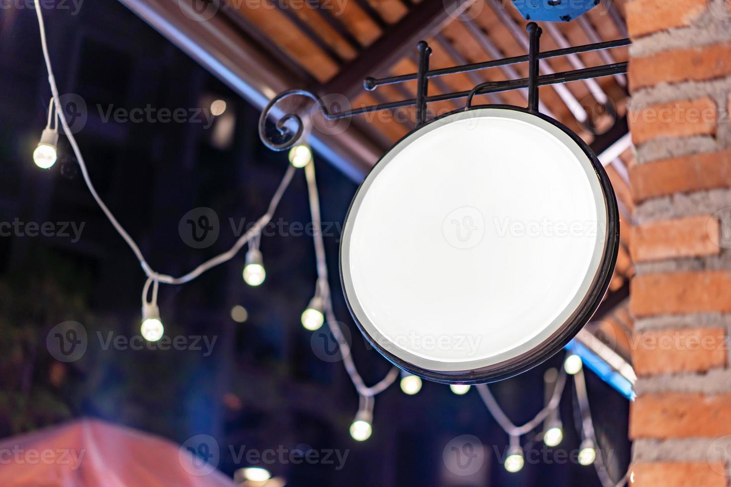 The Circle white Lightbox has hung on the wall in front of the brick pole in a Tungsten ambient environment vintage shopping community mall. photo