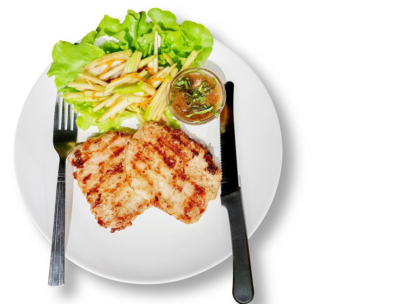 Top view fusion pork steak in Laos style with green apple on white plate and background. Steak Laos is a steak that combines Laos by tamarind sauce mixed rice crush with green apple as a side dish. photo