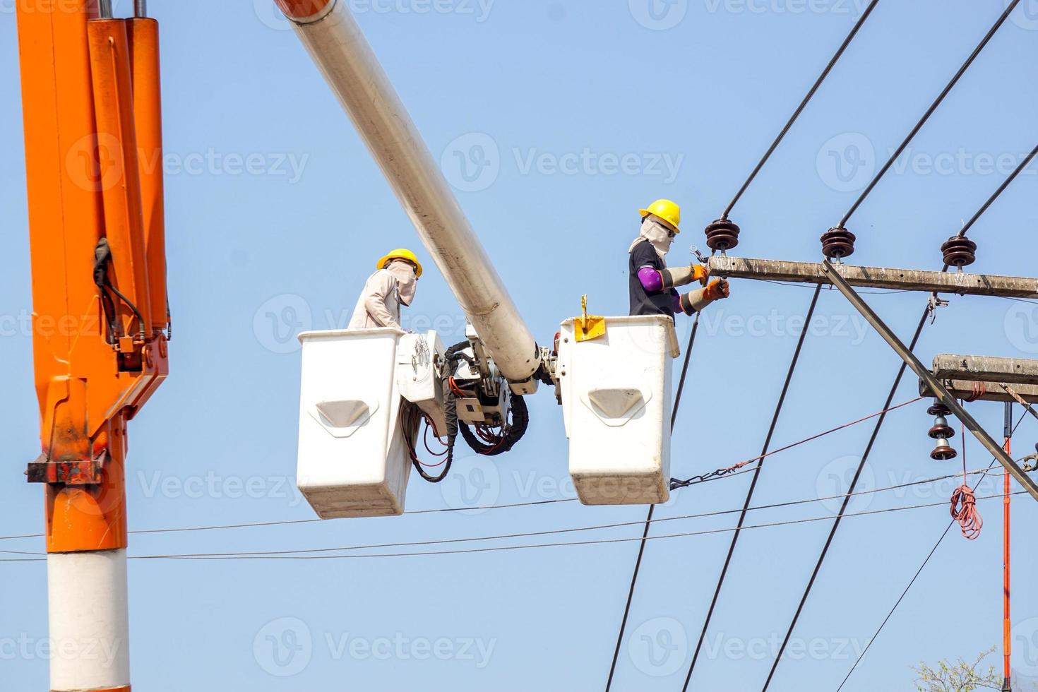 electricistas que trabajan en el teleférico para reparar la línea eléctrica bajo un fondo de cielo azul claro. foto