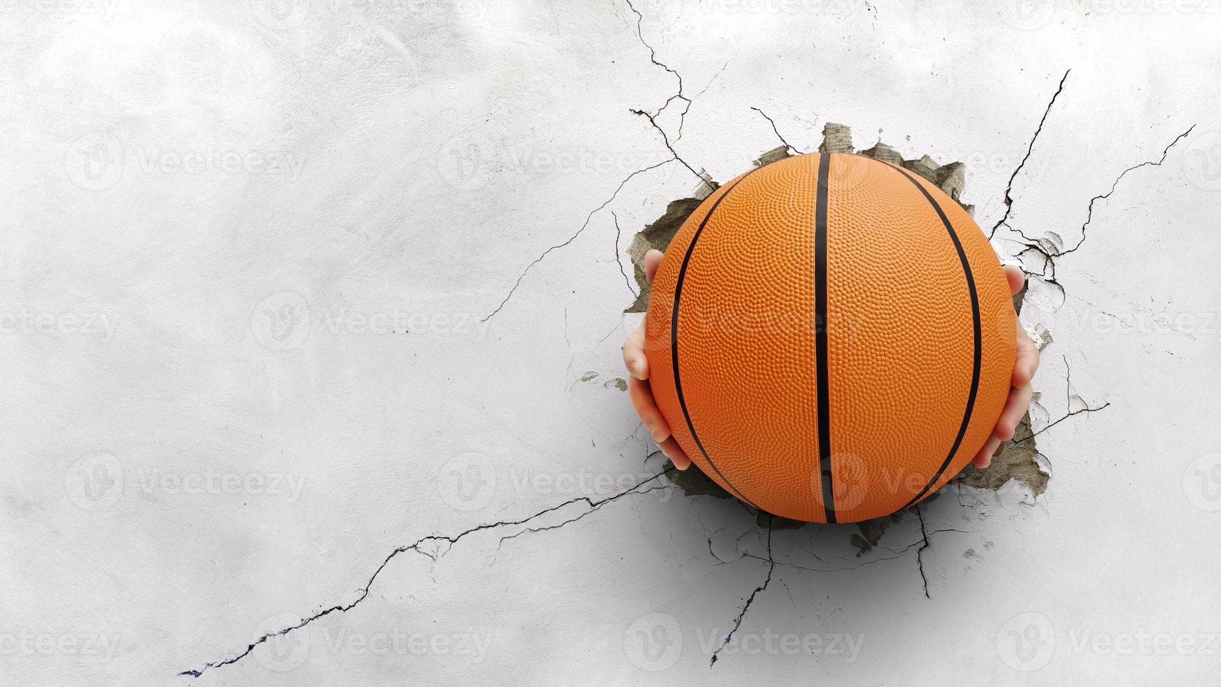 una mano que sostenía una pelota de baloncesto atravesó una pared de cemento. la fuerza del concepto de baloncesto foto