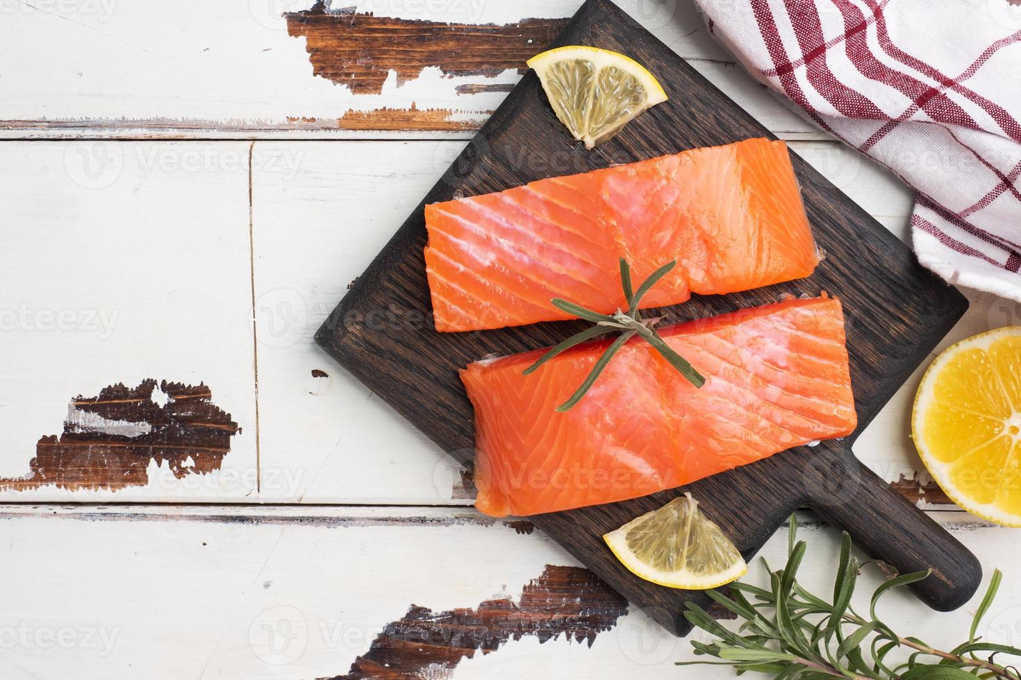 Salmon fillet, red salted fish on a wooden chopping Board. Lemon, rosemary spices. Copy space. photo