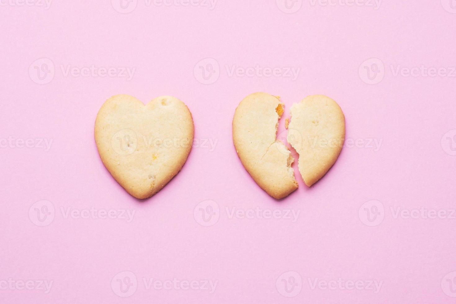 Heart shaped cookies, a cracked heart on a pink background, the concept of a broken relationship. photo