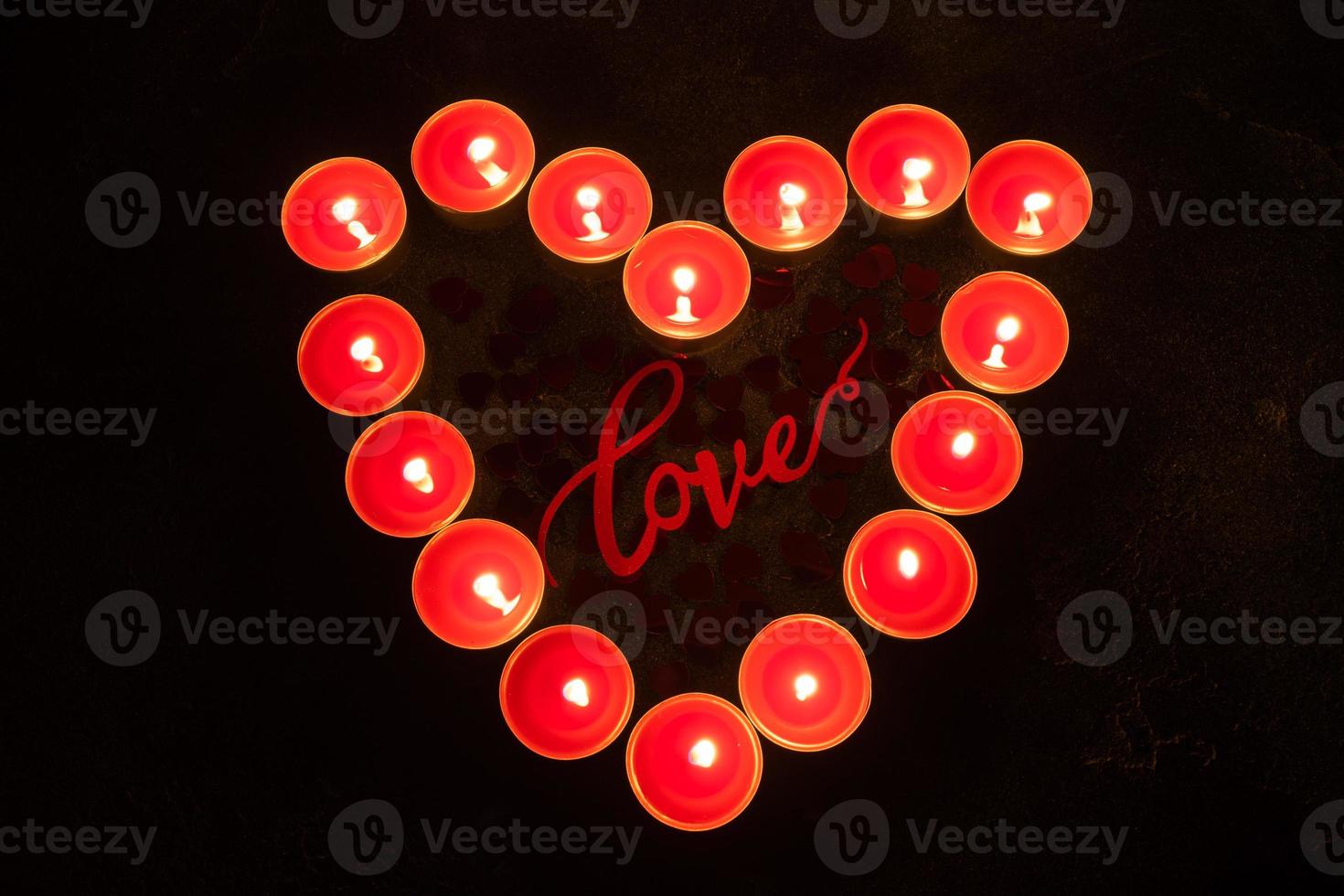 Red candles in the shape of heart on black background, concept of Valentine's Day. photo