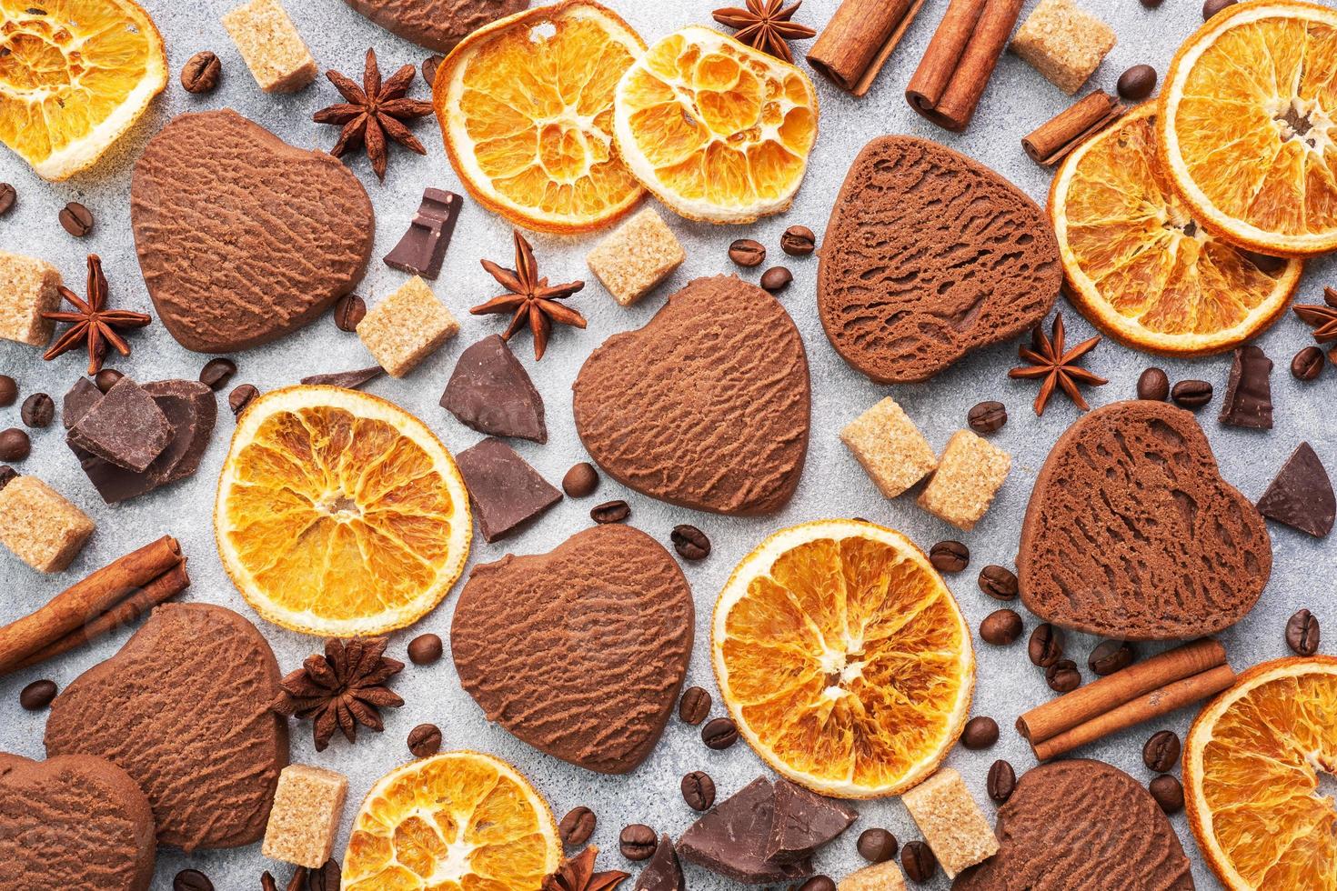Chocolate heart cookies, oranges cinnamon and spicy spices on a gray table, top view, close up. photo