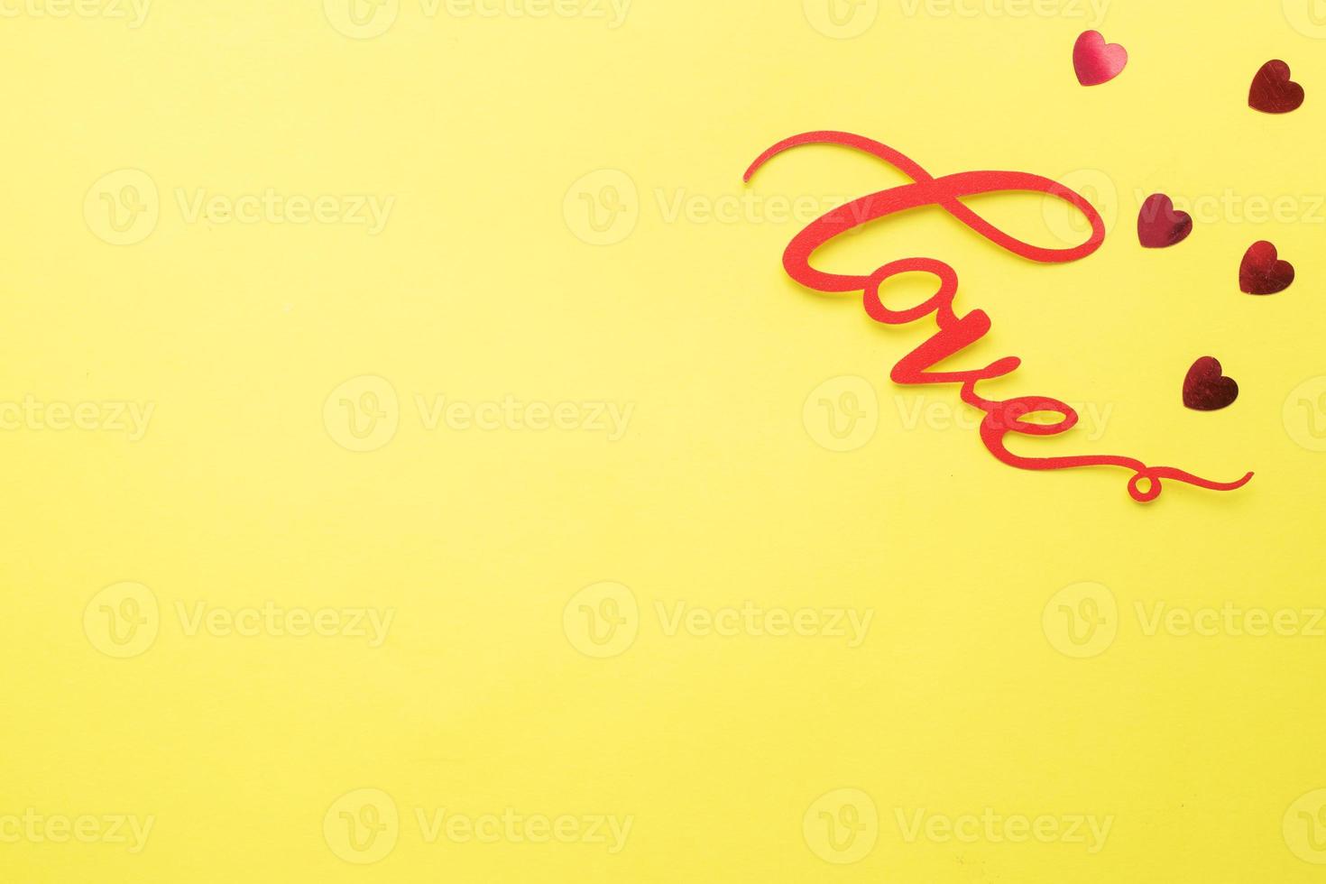 The word Love and red hearts on a yellow background, top view. Holiday card for Valentine's Day. Flat lay. photo