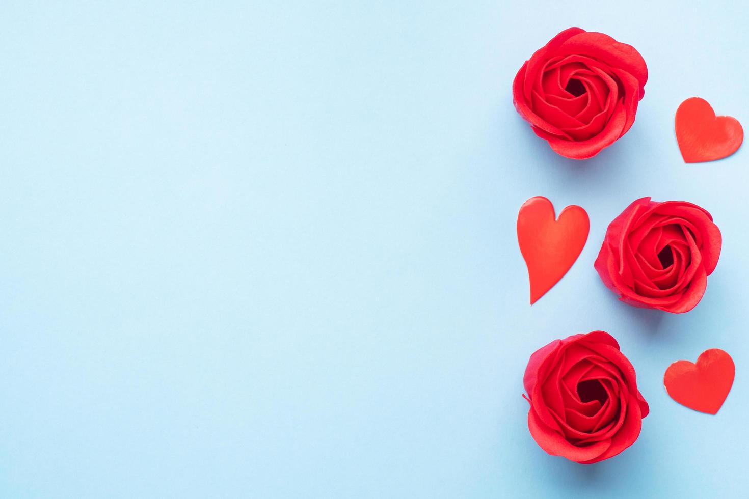 Handmade soap in the shape of a rose, red rose flower on a blue background. Top view, minimalist, copy space. photo