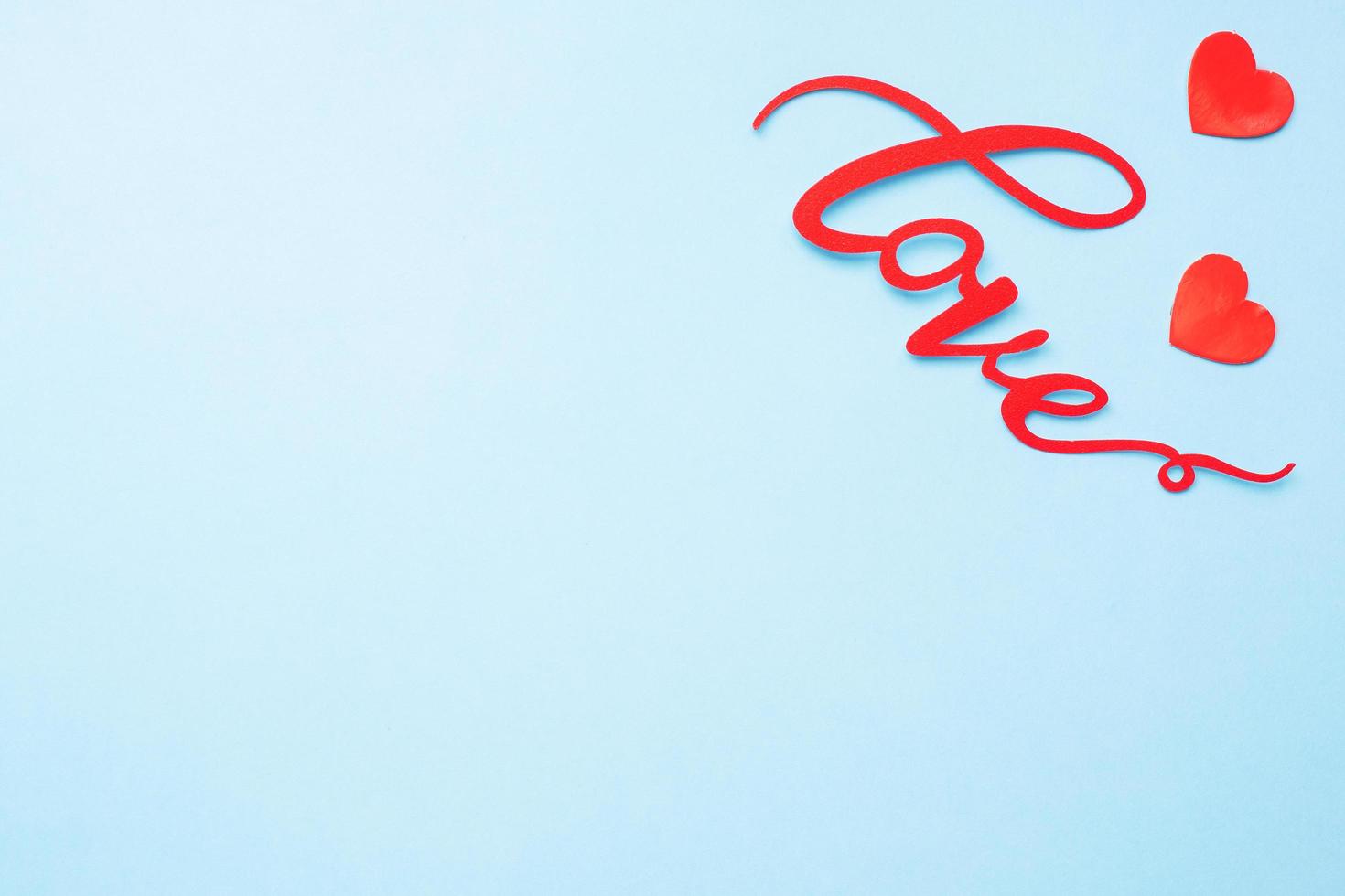 The word Love and red hearts on a blue background, top view. Holiday card for Valentine's Day. Flat lay. photo